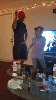 a man and a woman are dancing in a living room with a budweiser bottle on the table