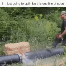 a man is walking next to a pipe in a field with a bunch of hay on it .