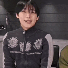 a young man wearing a black and white sweater is smiling .