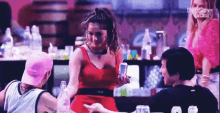 a woman in a red dress is holding a cell phone in a bar .