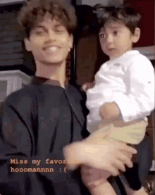a man is holding a small child in his arms and the caption says miss my favor hoomannnn .