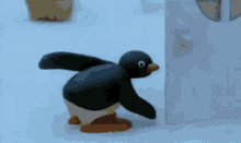 a cartoon penguin is walking in the snow near a door .