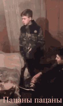 a man in a camouflage jacket is standing next to another man in a room with the words " пацаны пацаны " on the bottom
