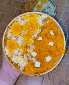 a person is holding a bowl of food with yellow and white sauce