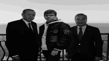 a boy wearing a jacket that says happiness on it poses for a picture with two men