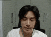 a man wearing headphones and a white shirt is sitting in a chair .