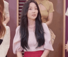 a woman with long black hair is sitting in front of a group of women in a room .