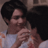 two young men are touching each other 's faces and one is holding something in his hand .