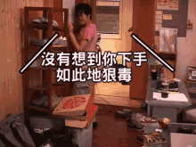 a man in a pink shirt is standing next to a stack of pizza boxes with chinese writing on them