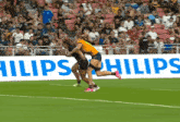 two female soccer players on a field with a philips ad in the background