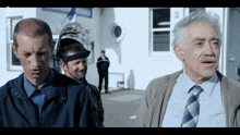 a man wearing a welding helmet talks to two other men