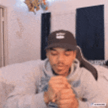 a young man wearing a hat is sitting on a bed .