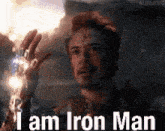 robert downey jr. is holding a glowing object in his hand and says `` i am iron man '' .