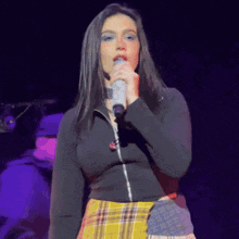 a woman is singing into a microphone on a stage