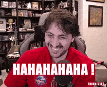a man in a red shirt is smiling in front of a sign that says ' hahahaha '