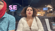 a woman sitting next to a man with the word se in pink behind her