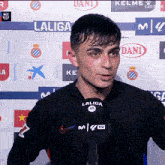 a man stands in front of a wall that has laliga and dani logos on it