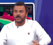 a man with a beard wearing a white sweater with a heart on it