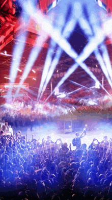 a crowd of people watching a concert with a blue light shining on them