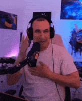 a man wearing headphones stands in front of a microphone with his hands on his chest