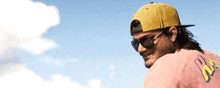 a man wearing sunglasses and a yellow hat with the letter a on his shirt