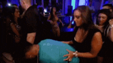 a woman is dancing with a man in a club while a crowd watches .