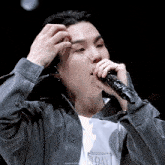 a close up of a person singing into a microphone with the letters agust visible