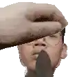 a hand is covering a man 's face with a piece of wood .