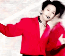 a man is wearing a red shirt and a microphone while dancing .