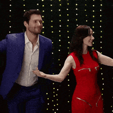 a man in a blue suit and a woman in a red dress are dancing together