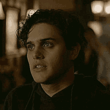 a young man with curly hair is wearing a black hoodie .