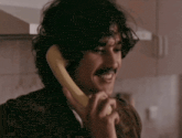 a man with a mustache is talking on a banana phone .