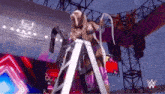 a woman is standing on a ladder in a stadium holding a belt .