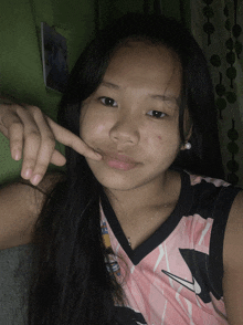 a girl wearing a pink nike tank top makes a peace sign