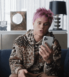 a young man with pink hair is looking at his phone