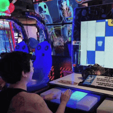 a man is playing a video game in an arcade with a sign that says caution