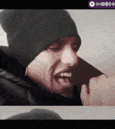 a man wearing a black beanie and a black jacket with a spotify logo on the bottom