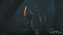 a poster for predator badlands shows a person laying on the ground in a cave