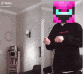 a man in a black hoodie is dancing in a living room with a pixelated face on his face .
