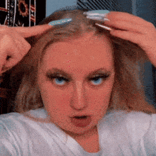 a woman with blue eyes is holding a hair clip in her hair and making a funny face