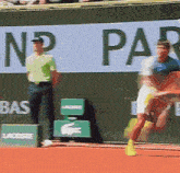 a man in a blue shirt is playing tennis in front of a sign that says np paribas