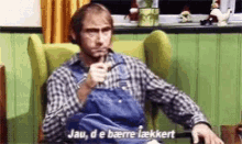 a man in a plaid shirt is sitting in a chair and pointing .