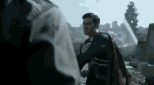 a man in a superman costume is standing in front of a destroyed city .