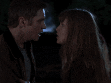 a woman is talking to a man in a dark room