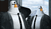 two penguins wearing suits and ties are standing next to each other with mountains in the background