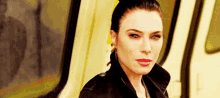 a woman in a black jacket is sitting on a bus .