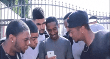 a group of men are looking at a cell phone together