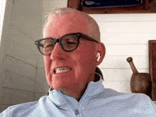 a man wearing glasses and ear buds looks at the camera