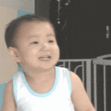 a baby is wearing a white tank top and a blue collar .