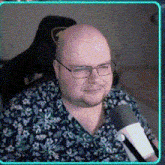a bald man with glasses and a beard is holding a microphone .